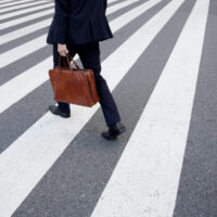 a pedestrian carrying a brown briefcase a pedestrian carrying a brown briefcase